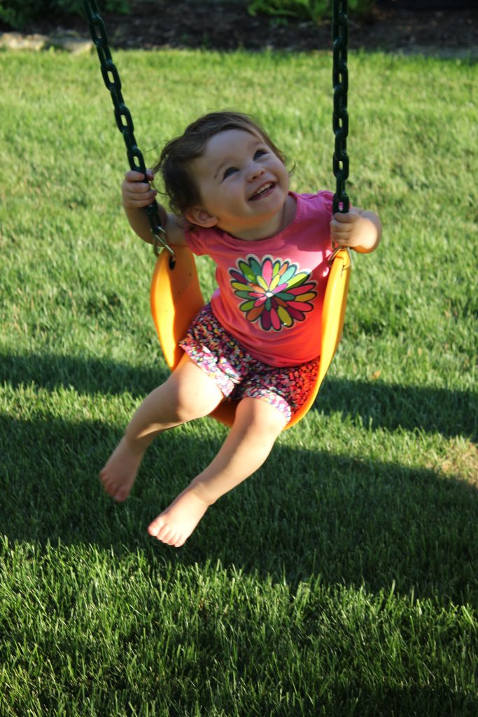 young child playing on swing set smiling