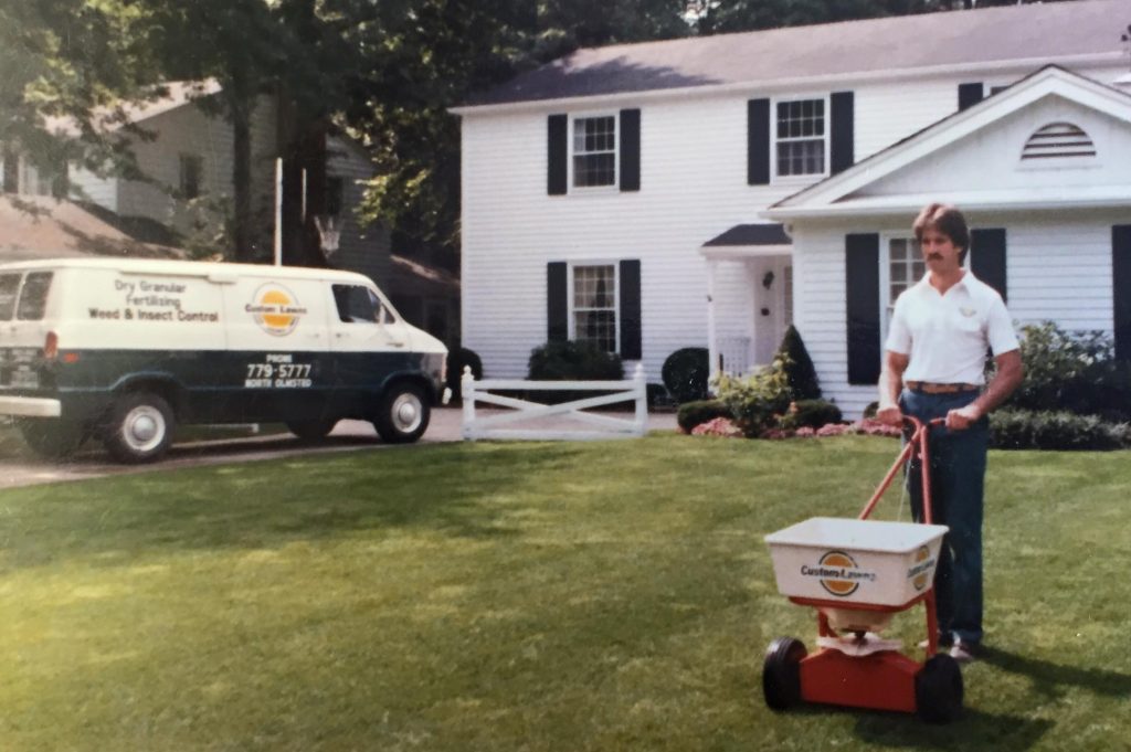 older photo of man seeding grass